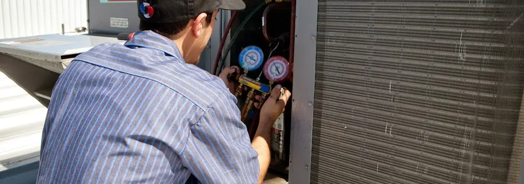 HVAC technician servicing a condenser unit in Bellefonte